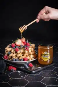 Good Morning Honey liquid honey is drizzled over waffles and fruit
