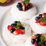 Meringues are topped with mixed fruits and blueberry honey.