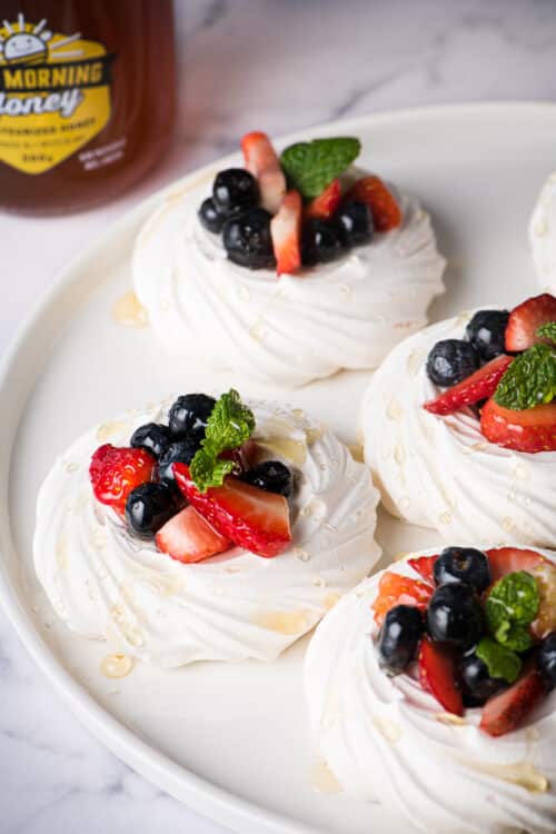 Meringues are topped with mixed fruits and blueberry honey.